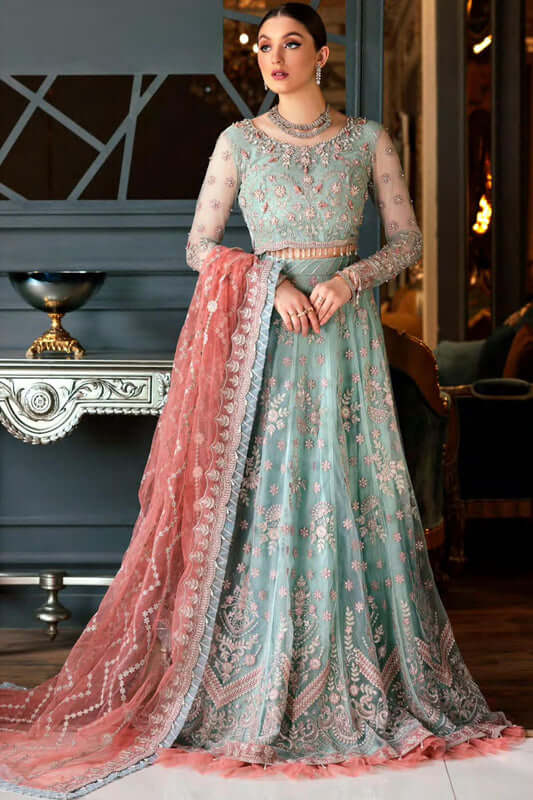 ''Woman wearing a traditional outfit with a light blue top and pink dupatta in an indoor setting.''